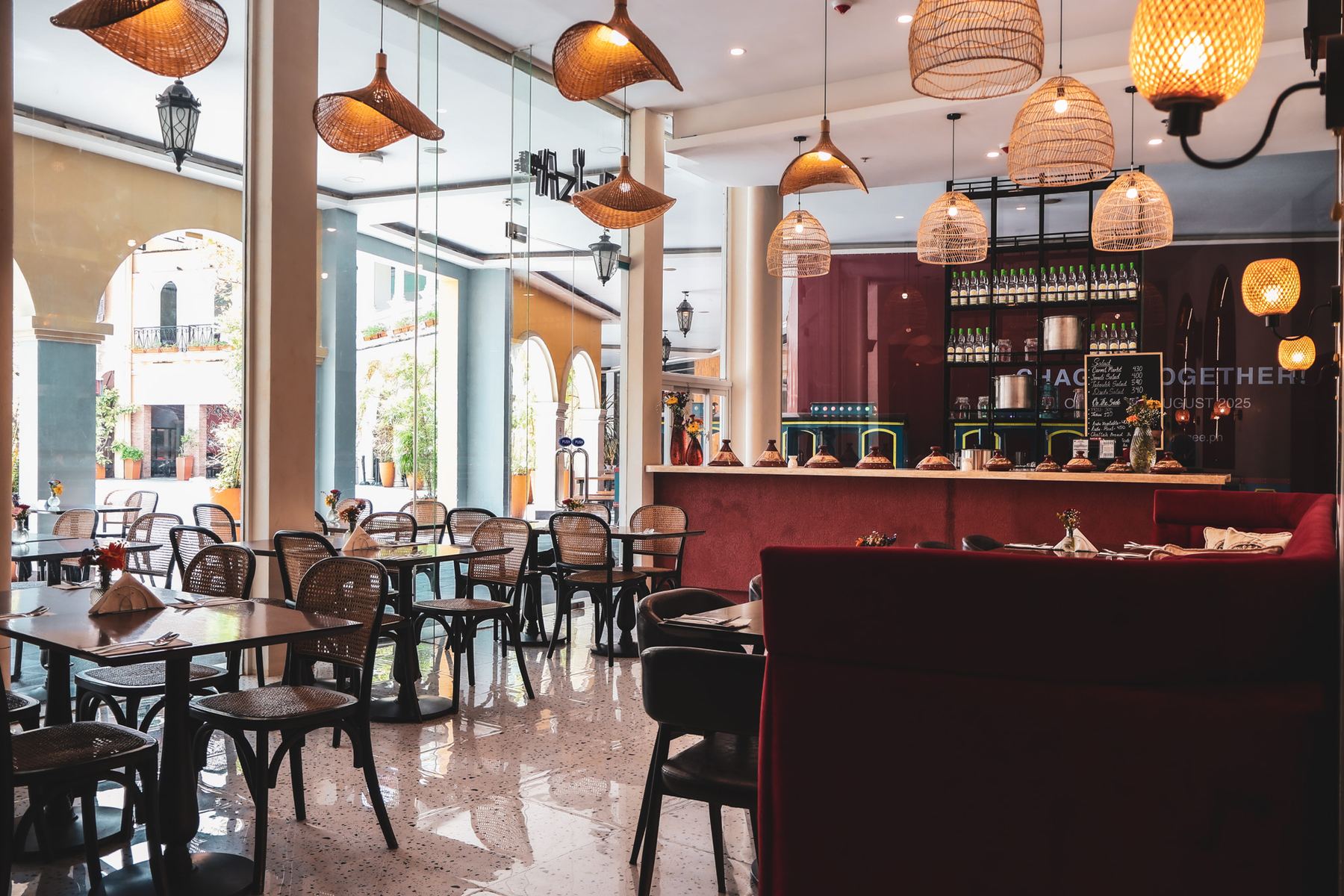 The dining room at Aziza, with burgundy banquettes, cane chairs and brass lights